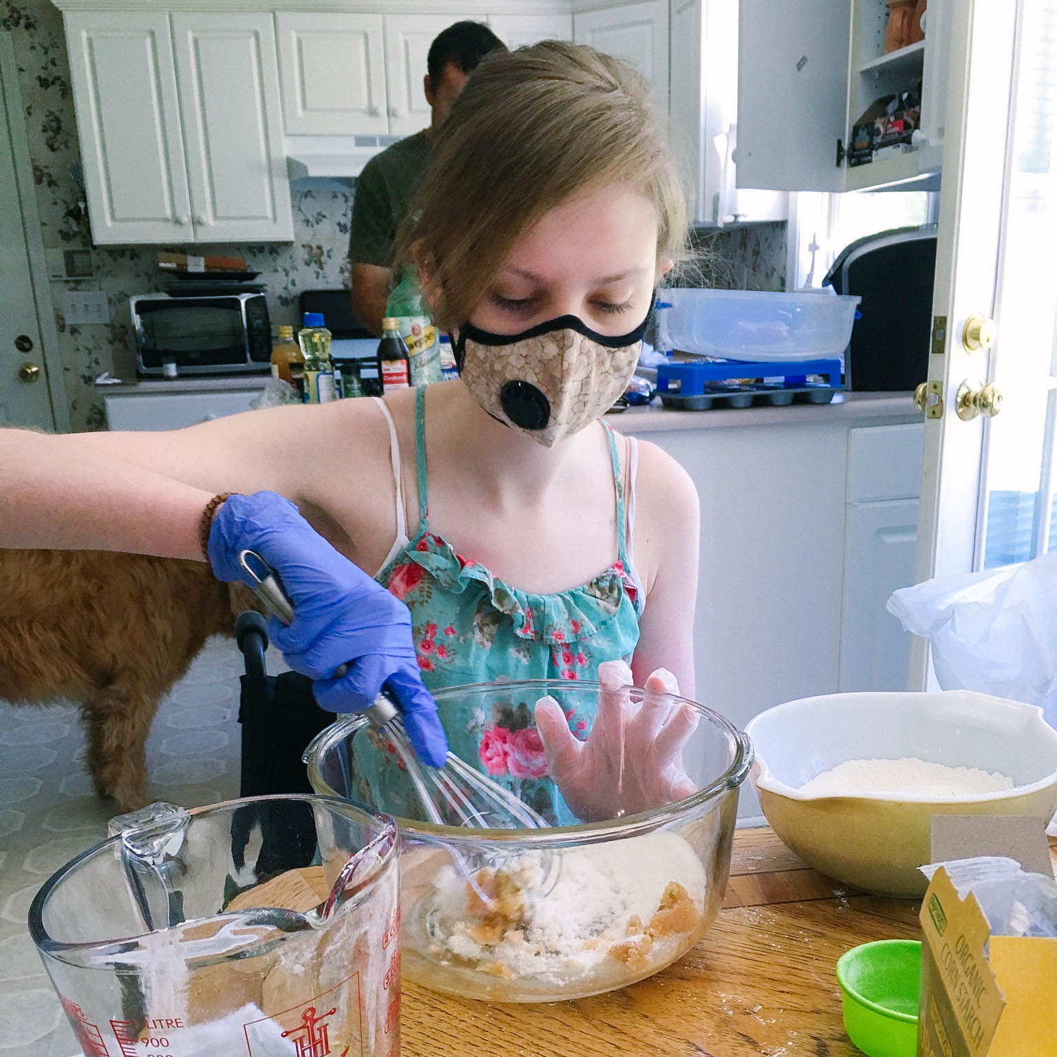 Cheyanne baking in her kitchen - “Mast Cell Disease renders me airborne reactive to foods” – hence the mask